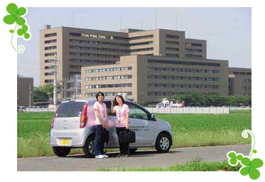埼玉医科大学総合医療センター建物と訪問看護ステーションスタッフの写真